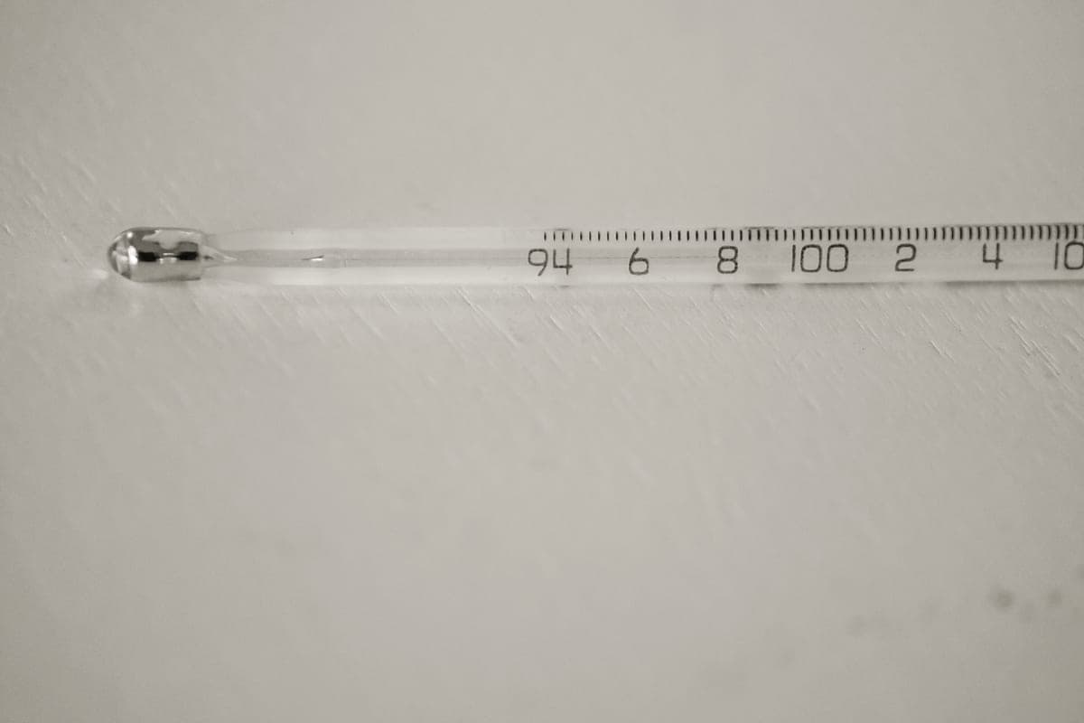 A thermometer beside a small aquarium, reading the water temperature