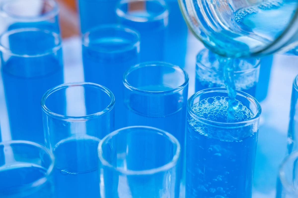 Blue liquid being poured into glass test tubes